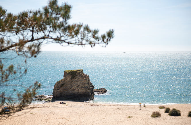 View of the rocky outcrop reaching out of the sand at Carlyon Bay in South Cornwall