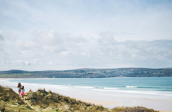 Two children standing in the sand dunes looking out over Hayle Towans Beach in Cornwall