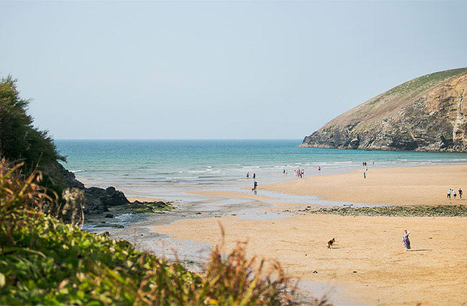 Golden sands and towering cliffs at Mawgan Porth beach in Cornwall