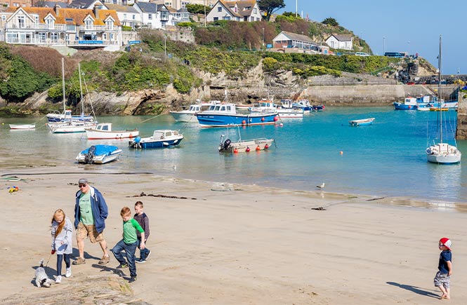 A family walking their dog on Newquay Harbour Beach in Cornwall