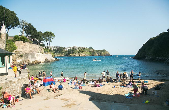 The small sandy Readymoney Cove full of people enjoying the sun and sea
