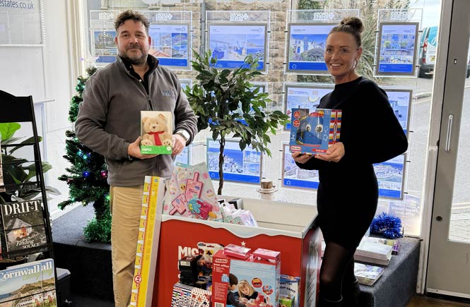 Two people hold gifts next to the gift donation point.