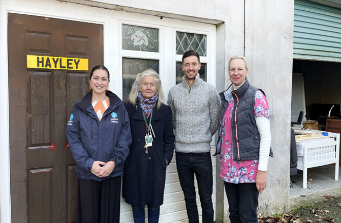 four people, from Hidden Help and Aspects Holidays, stand in front of the warehouse named Hayley