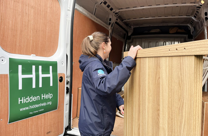 A lady helps lift a bed frame into the van