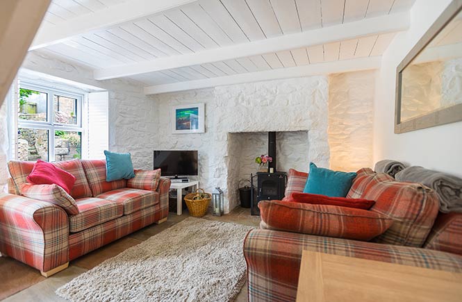 Two comfortable sofas and a woodburner make a cosy lounge in this Cornish cottage