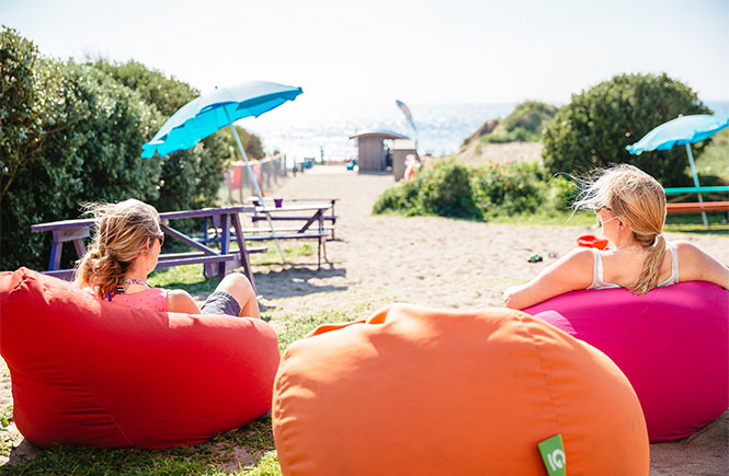 People sitting on bean bag chairs overlooking the beach at The Break Beach Bar in Cornwall