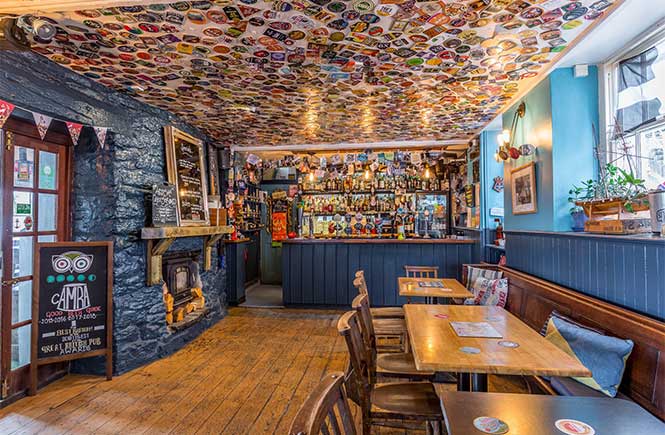 The cosy bar area at The Boathouse, with blue walls and hundreds of beer mats on the ceilings