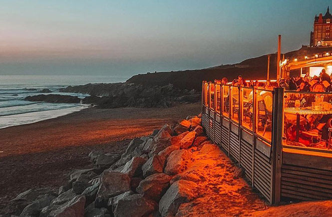 The wooden terrace at Fistral Beach Bar at night overlooking the beach