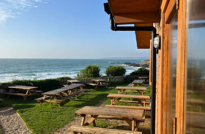 Outdoor tables overlooking the beach and sea at Cabin Beach Café in Cornwall