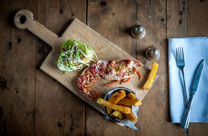 A lobster and chips on a wooden board at Port Gaverne Restaurant and Hotel