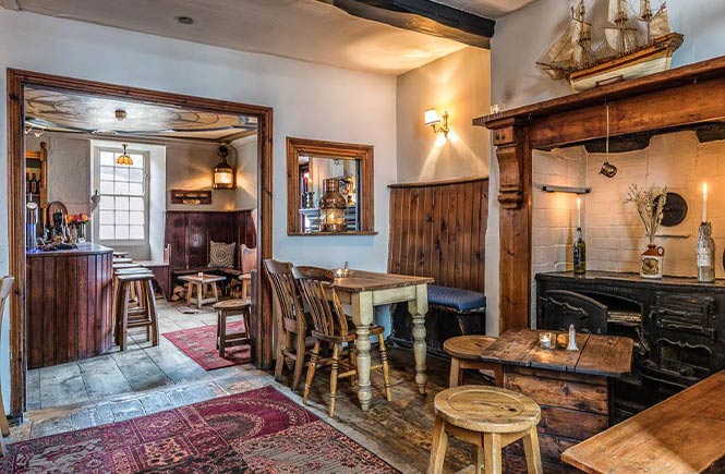 Lots of tables and chairs around a fireplace at The Golden Lion in Port Isaac