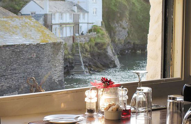 A table next to a window overlooking Port Isaac harbour at The Mote