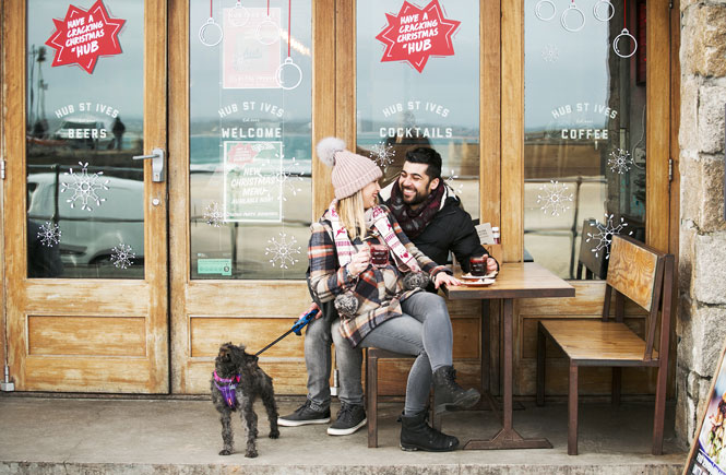 A couple with their dog sitting outside Hub St Ives at Christmas