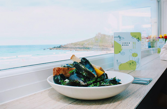 A bowl of mussels overlooking the beach at Porthmeor Beach Café in Cornwall