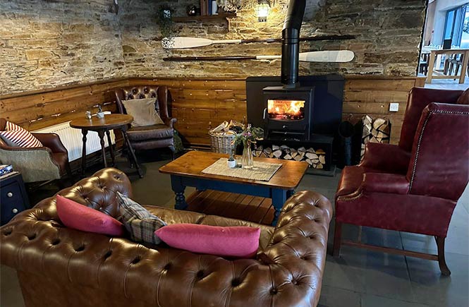 Comfy sofas and chairs around a cosy fire at The Port William pub in Cornwall