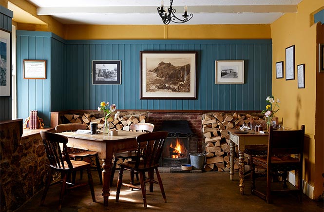 The cosy dining room with a fireplace at The Gurnard's Head pub in Cornwall