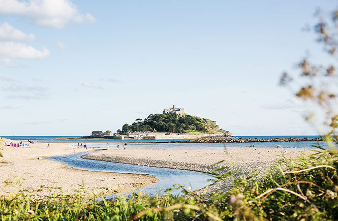 Looking across a sandy beach at St Michael's Mount, a castle on a tidal island