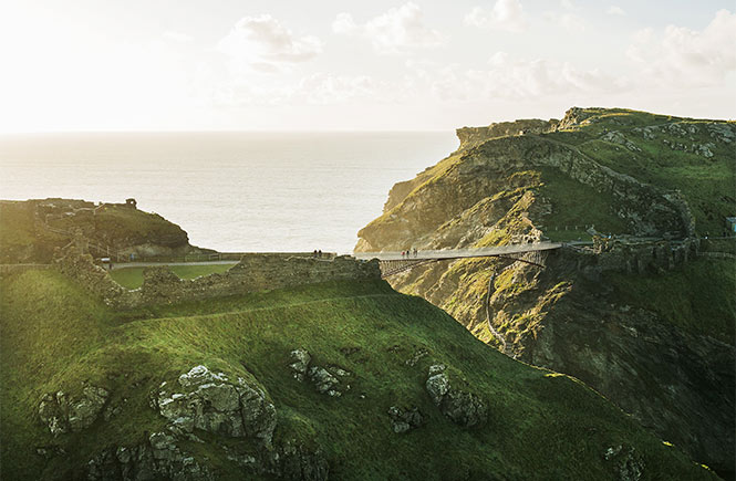 The ancient ruins of Tintagel Castle on the cliffs in Cornwall, with an impressive bridge in the distance