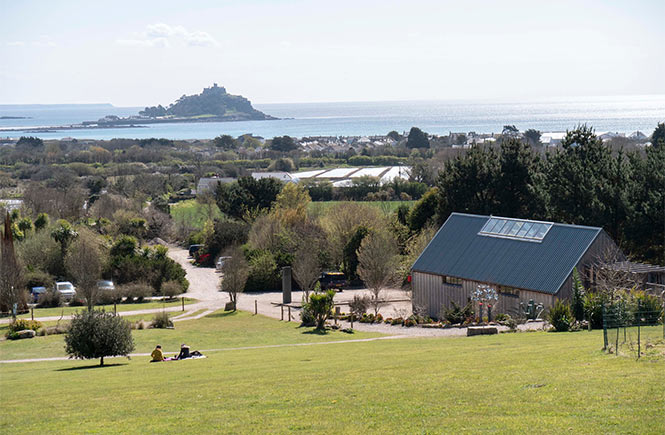 Clean cut lawns, a wooden building, and St Michael's Mount in the distance at Tremenheere Sculpture Gardens in Cornwall