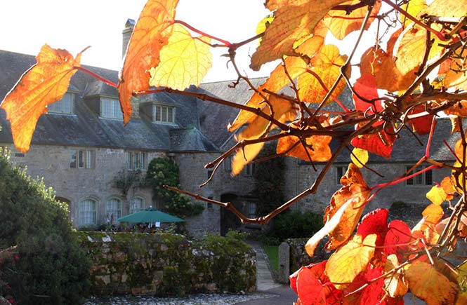 Red, yellow and orange leaves frame Trerice House.