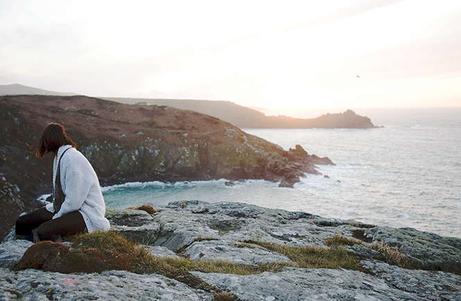 Someone sat on the cliffs overlooking the sea and rugged coastline at Zennor near St Ives