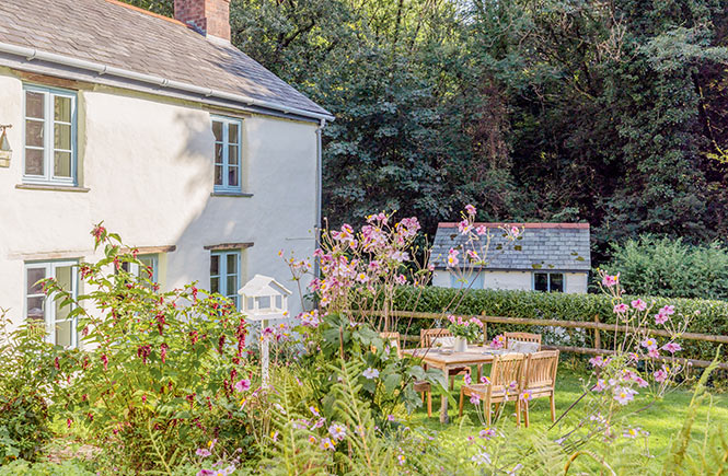 Trees and shrubbery surround a quaint cottage