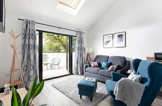 A light and airy lounge features plush sofas and a large window and velux.