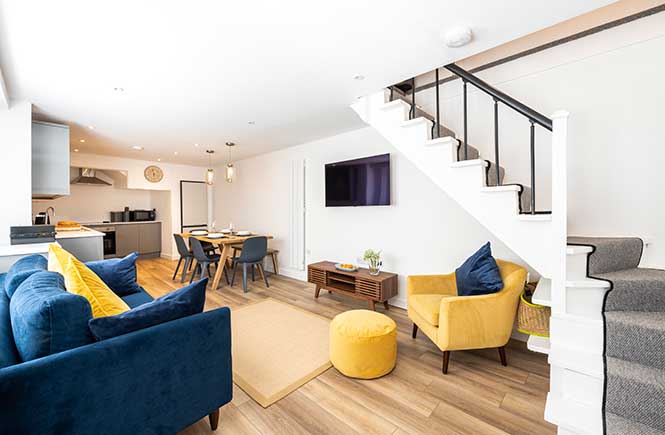 An open plan living space is bright and colourful with a blue and yellow theme.