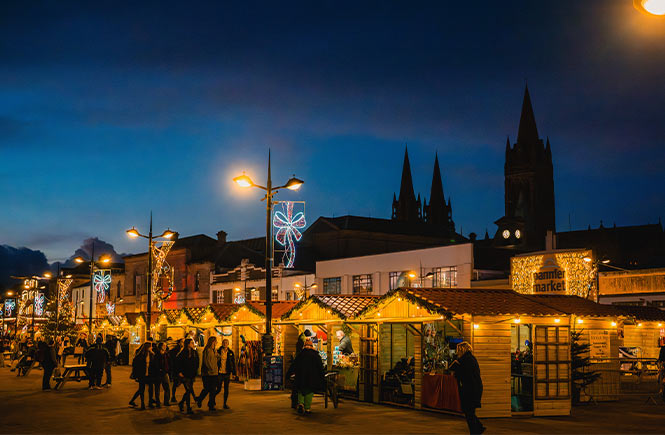 The bustling Truro Christmas Market with lots of stalls and Truro Cathedral in the distance