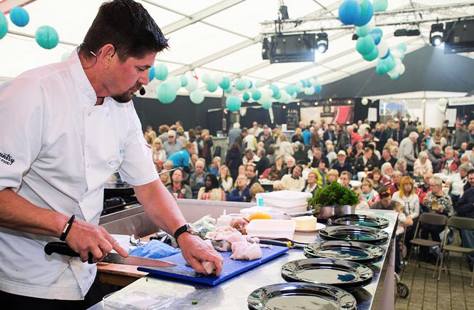 A chef performing a cookery demo in front of a crowd at Falmouth Oyster Festival in Cornwall