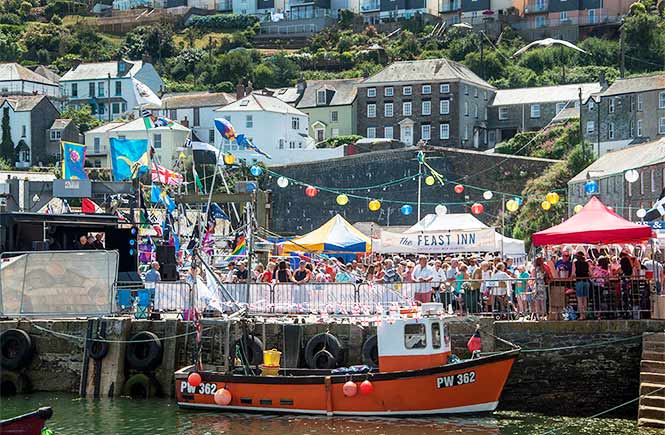 Looking across the harbour at a crowd and celebrations during Mevagissey Feast Week