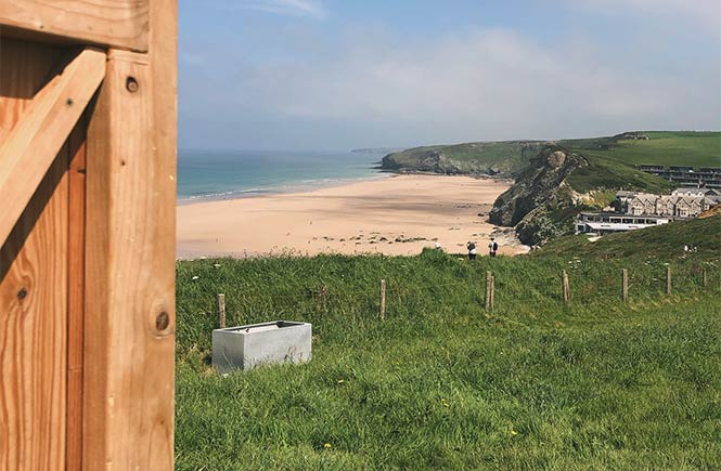 Looking past Olla Hiki's clifftop sauna at the golden sands of Watergate Bay in Cornwall