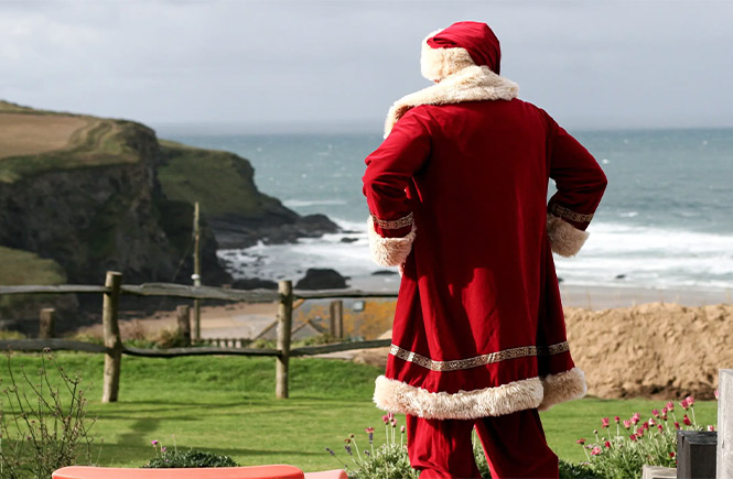 Father Christmas standing on the cliffs and looking out to sea at Bedruthan Hotel and Spa