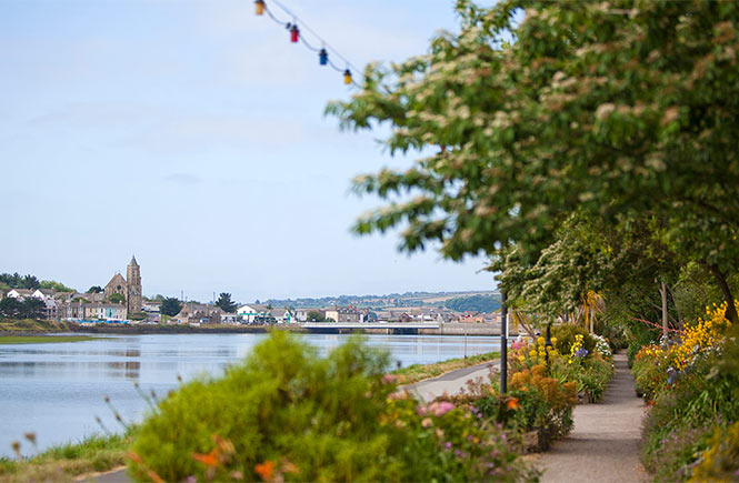 The pretty, flower-lined path by the water at the King George V Memorial Walk in Hayle
