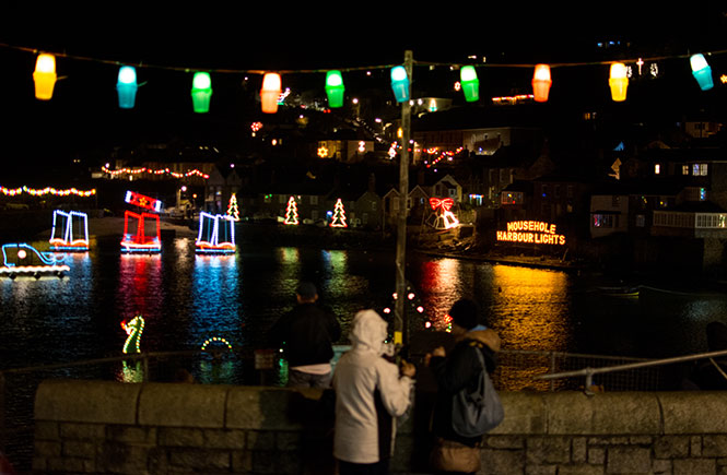 People looking out over the Christmas lights in Mousehole harbour on Tom Bawcock's Eve
