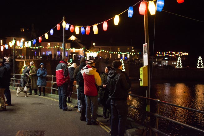 A group of people gathered to look at the Christmas lights around Mousehole harbour on Tom Bawcock's Eve