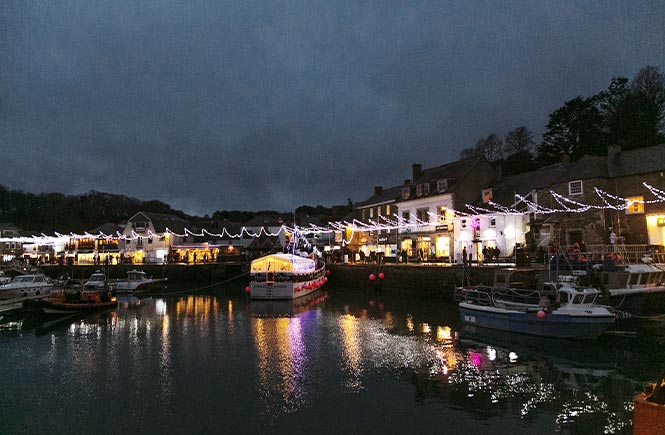 Looking across Padstow harbour at night with Christmas lights glowing in the dark