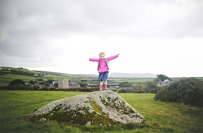 A child standing on a rock in a field near Zennor